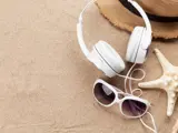 Solbriller, hat, hørebøffer og søstjerne i sand
